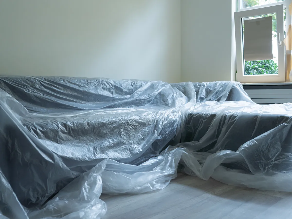 Mit Schutzfolie abgedecktes Sofa in einem frisch renovierten Raum