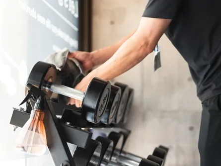 Kurzhanteln im Fitnessstudio werden mit einem Tuch abgewischt