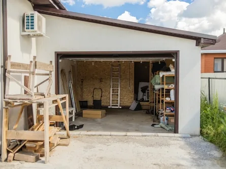 Geöffnete Garage mit Regalen, Holz und abgestellten Gegenständen