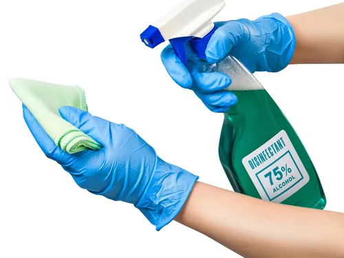 Hände in Schutzhandschuhen mit Desinfektionsspray und Reinigungstuch