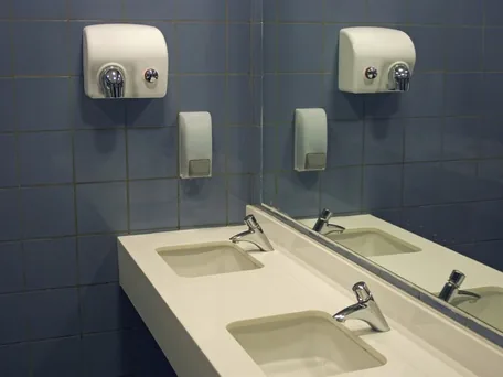 Sauberer Waschraum mit Waschtisch, Armaturen und Händetrockner