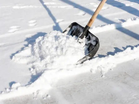 Schneeschaufel beim Räumen eines verschneiten Wegs