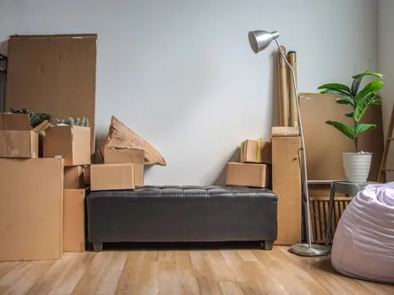 Gepackte Umzugskartons und Möbel in einer Wohnung mit Parkettboden
